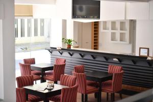 a restaurant with red chairs and tables and a counter at O2 Hotel Gualeguaychú in Gualeguaychú