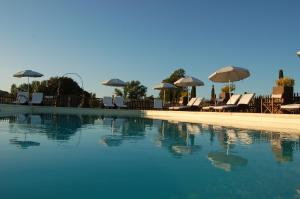 a swimming pool with chairs and umbrellas at Bed and Breakfast Casale del Sole in Castellina Marittima