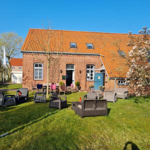 a brick house with chairs and tables on a yard at Hotel Restaurant Kastanjehoff in Timmel