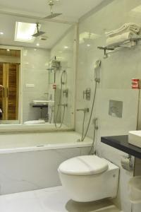 y baño con aseo, ducha y lavamanos. en Hotel Aman Continental - Paharganj en Nueva Delhi