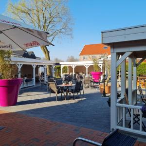 eine Terrasse mit Tischen, Stühlen und Gebäuden in der Unterkunft Hotel Restaurant Kastanjehoff in Timmel