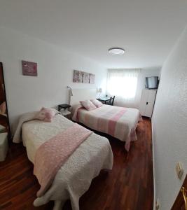 um quarto com 2 camas com lençóis cor-de-rosa e brancos em Pension Toñi em Belorado