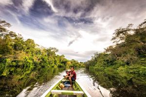 a man and a child riding in a boat on a river at Libertad Jungle Lodge in Yucuruche