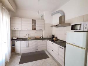 uma cozinha com armários brancos e um frigorífico branco em Casa Bagai em Milão