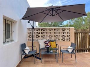un patio con 2 sillas y una mesa con sombrilla en Apartamentos Carabela en Playa Migjorn