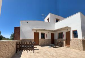 a white house with wooden chairs and a wall at Apartamento La Solanita, Artenara in Artenara