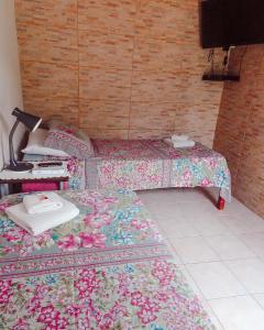 um quarto com duas camas com uma colcha com flores em Pousada Alquimia em Jericoacoara