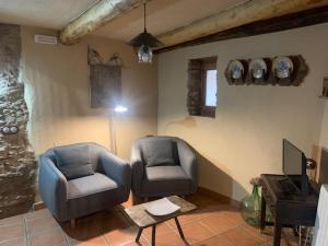 a living room with two chairs and a television at Caserío de Ovejuela in Ovejuela