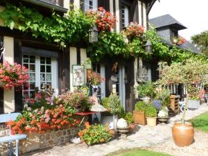 un edificio lleno de flores y plantas en La Ferme Du Pressoir Guest House, en Conteville