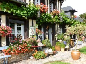 a building filled with lots of flowers and plants at La Ferme Du Pressoir Guest House in Conteville