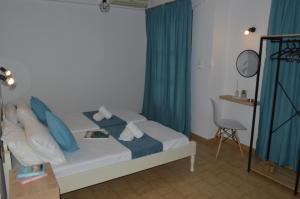 a bedroom with a bed with blue curtains and a table at Pansion Katerina in Skiathos Town