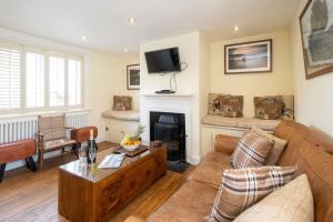 uma sala de estar com um sofá e uma lareira em Pebble Cottage - 6 Victoria Rd - Aldeburgh Coastal Cottages em Aldeburgh