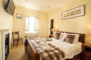 um quarto com uma cama, uma televisão e uma lareira em Pebble Cottage - 6 Victoria Rd - Aldeburgh Coastal Cottages em Aldeburgh