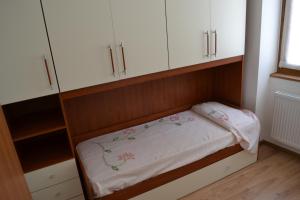 Cama pequeña en habitación con armarios blancos en Casa Ledro, en Ledro
