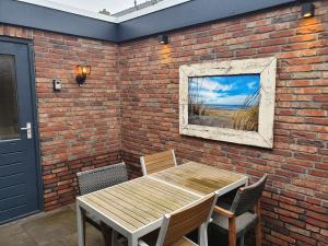 a brick wall with a wooden table and chairs at Knus huisje met prachtige nieuwe badkamer - Distelhoek in Egmond aan Zee
