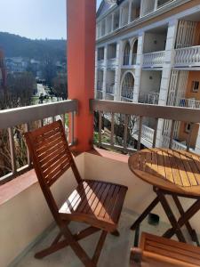 2 Stühle und ein Tisch auf einem Balkon mit einem Gebäude in der Unterkunft studio tout équipé proche therme in Lamalou-les-Bains