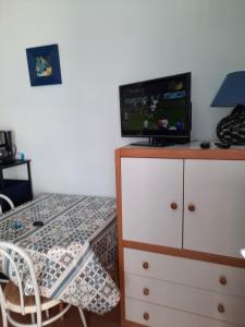 ein Schlafzimmer mit einem Tisch und einem TV auf einer Kommode in der Unterkunft studio tout équipé proche therme in Lamalou-les-Bains