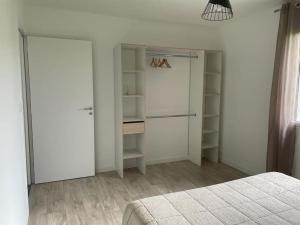 a white bedroom with a closet and a bed at Maison de vacances in Poilley