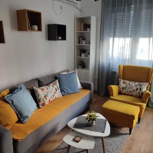 uma sala de estar com um sofá e uma cadeira em Center Firefly Gardens Apartment em Novi Sad
