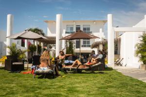 eine Gruppe von Menschen, die vor einem Haus auf Gartenstühlen sitzen in der Unterkunft Hotel La Ría Playas in Playas