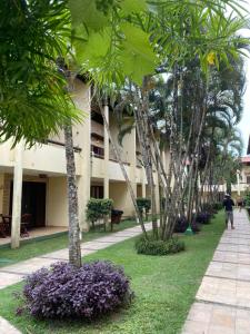 eine Person, die einen Bürgersteig neben einem Gebäude mit Bäumen entlanggeht in der Unterkunft Apartamentos no Solar Pipa in Pipa