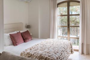 um quarto com uma cama branca com almofadas vermelhas e uma janela em Estudio Plaza de la Laguna by Dulce em Ayamonte