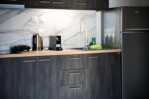eine Küche mit einer Theke mit einer Spüle und einem Kühlschrank in der Unterkunft *Oasis* Best View Jacuzzi New Central Apartment in Volos