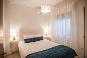 a bedroom with a bed with two pillows and a window at Apartamento Plaza de la Laguna by Dulce in Ayamonte