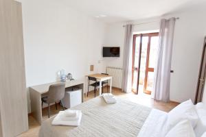 a white bedroom with a bed and a desk and a deskablish at La Villa Carmelina in Agerola