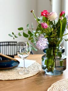 einen Tisch mit einer Vase aus Blumen und einem Weinglas in der Unterkunft SUNSET APARTMENT: FREE PARKING + BALCONY + NETFLIX in Essen