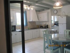 a kitchen with white cabinets and a table and chairs at Le Pijolin in Saint-Justin
