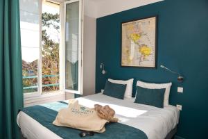 a bedroom with a bed with a stuffed animal on it at The Originals Boutique Hôtel La Villa Ouest & Spa in Saint-Palais-sur-Mer