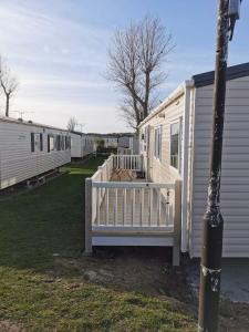 a white mobile home with a porch and a fence at Riverside 11 PARKDEAN South Beach Heacham in Heacham