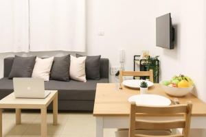 a living room with a couch and a table with a laptop at Paris Square Apartments Downtown in Haifa
