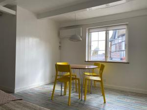 mesa de comedor con sillas amarillas y ventana en Tinyhouse Thorøhuse en Assens
