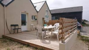 una terraza de madera con mesa y sillas. en Ty cocooning, en Kerlouan