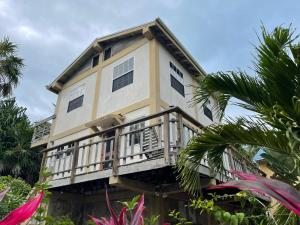 a building with a balcony and palm trees at Alta Vista Vacation Home in Caye Caulker