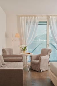 a living room with two chairs and a large window at Hotel Villa Aurora in Lezzeno