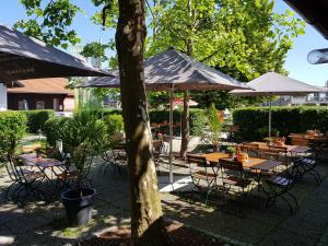 eine Gruppe von Tischen und Stühlen mit Sonnenschirmen in der Unterkunft Gasthof zur Strass in Eugendorf