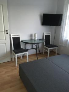 Habitación con mesa, 2 sillas y TV. en Pokoje u Asi en Augustów