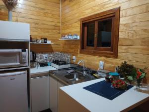 a kitchen with a sink and a microwave at Quinta dos Ventos Chalé in Urubici