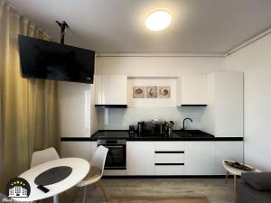 - une cuisine avec des placards blancs, une table et des chaises dans l'établissement Black Sea Booking-London, à Mamaia Nord – Năvodari