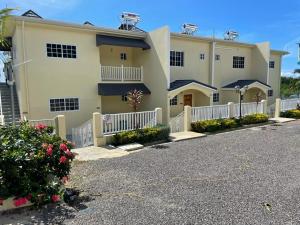 um grande edifício amarelo com uma cerca branca em Westmore Beach Villas Limited em Whitehouse