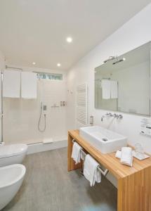 bagno bianco con lavandino e servizi igienici di Hotel Villa Aurora a Lezzeno