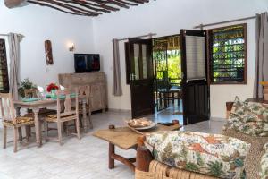 salon ze stołem, krzesłami i telewizorem w obiekcie Amani Paradise - Luxury Villas w mieście Diani Beach