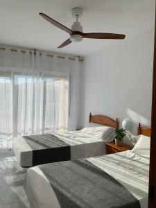 two beds in a bedroom with a ceiling fan at Apartamento en primerísima línea de playa con espectaculares vistas Netflix, Prime y Disney in Oropesa del Mar