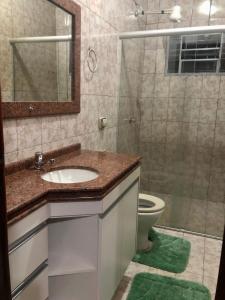 a bathroom with a sink and a toilet and a mirror at Casa 3/4 com piscina e mesa de sinuca em Caldas Novas in Caldas Novas