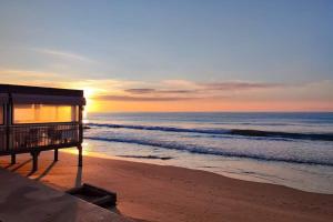 a building on the beach with the sunset in the background at b&b La Rosa dei venti in Alassio