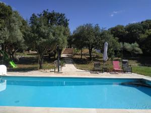 a swimming pool with two chairs and an umbrella at Argelliers in Argelliers