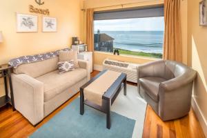 a living room with a couch and a chair and a window at Three Arch Inn in Oceanside